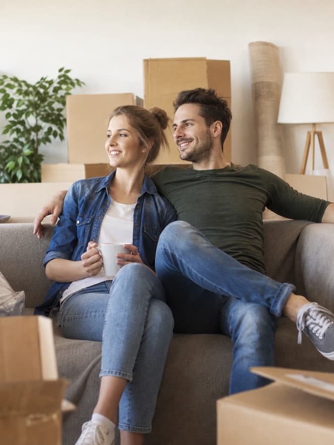 Paar sitzt zwischen Umzugskartons auf dem Sofa